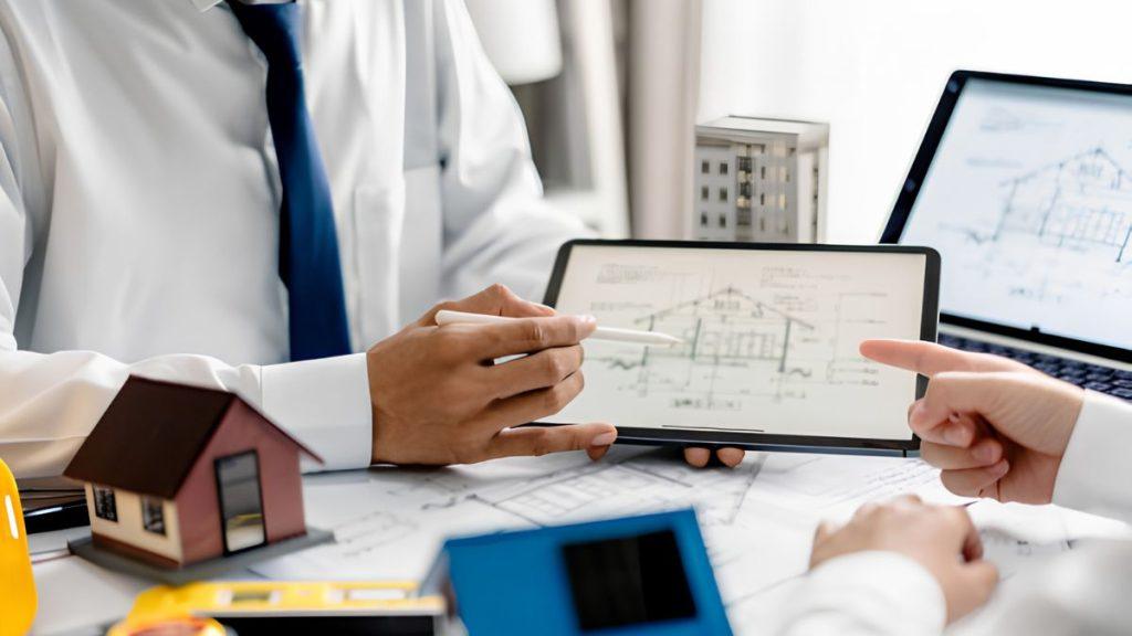 Contratos-quantium-desarrollos-sector-inmobiliario-monterrey - Apoyo Regio Two Professionals Review Architectural Plans on a Tablet, with a Small House Model and Construction Tools on the Desk. - Apoyo Regio