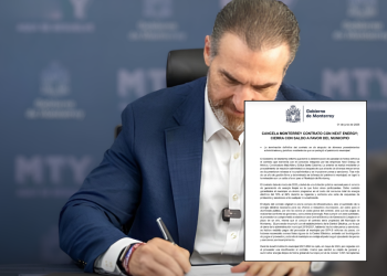 Man in a Blue Suit Signs a Formal Government Contract Document at a Desk, Mty Logos Visible in the Blurred Background - Apoyo Regio