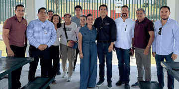 Group of Eleven Adults Standing Together Outdoors, Posing for a Casual Team Photo Under a Pavilion. - Apoyo Regio
