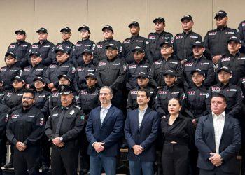 personnel in matching black jackets and caps posing for a photo indoors.