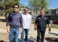 Three Men Wearing Button-down Shirts Walk on a Sunny Sidewalk, Looking Ahead with Serious Expressions. - Apoyo Regio