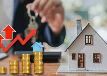 Miniature house beside stacked coins and a rising red arrow, illustrating growing real estate investment wealth (background person with keys).